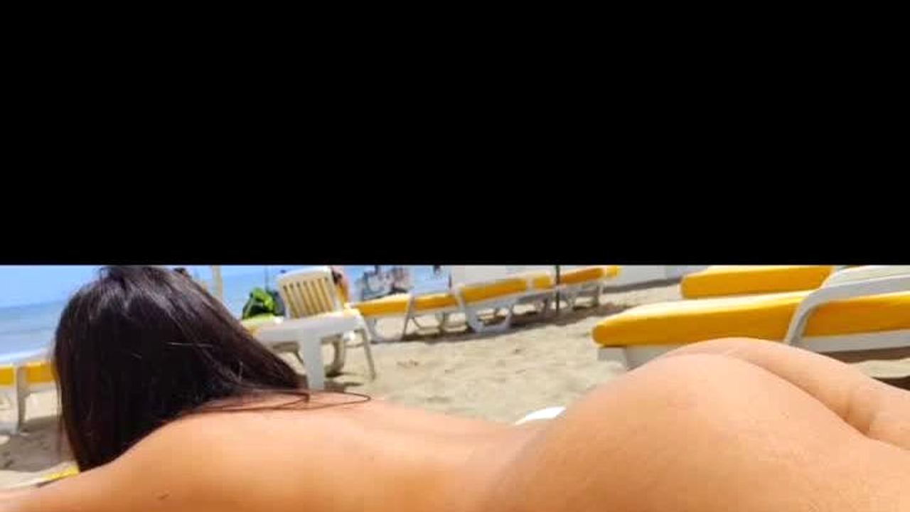 Manden filmer sin kone nøgen på stranden, mens hun soler sig i offentligheden